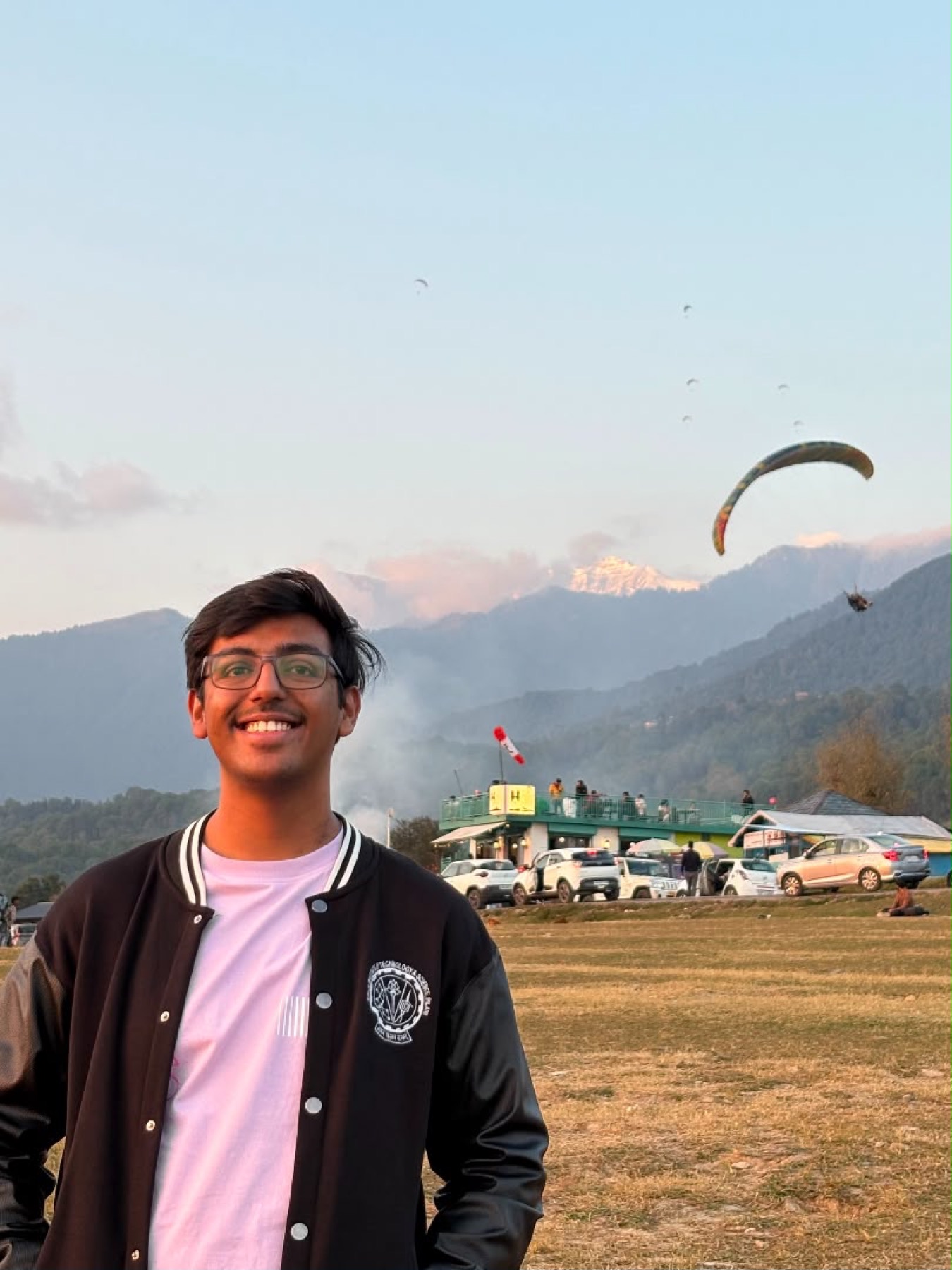 Harshit smiling with mountains and paragliders behind him